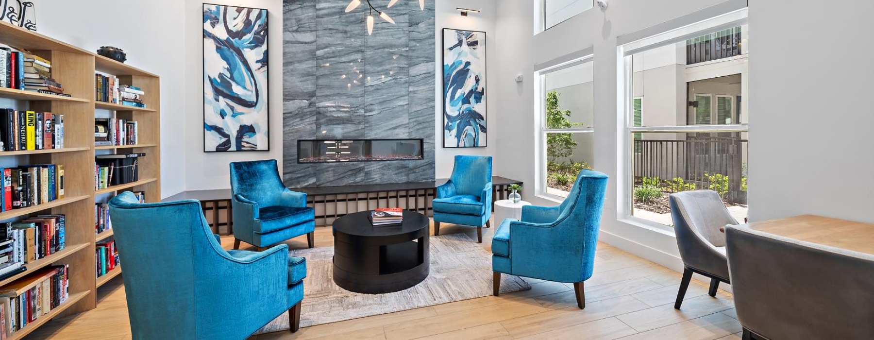 a lounge with blue chairs and a table with a bookcase