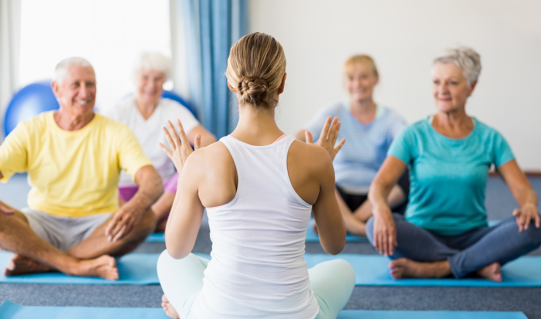 a group of people sitting during a yoga session looking at the instructor